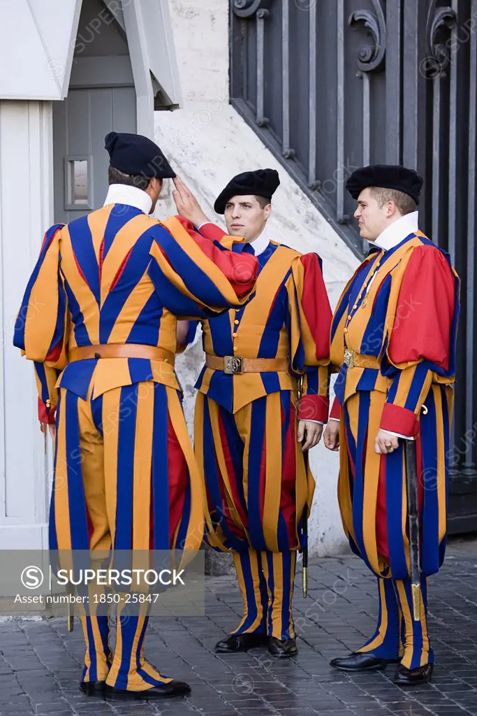 Italy, Lazio, Rome, Vatican City Three Swiss Guards In Full Ceremonial Uniform Dress With Two Saluting Each Other