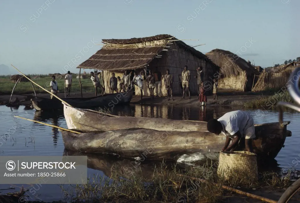 Malawi, Chilwa, Yau Tribe Fishermen With Yav Boats On Lake Chilwa. Men And Children Gathered Next To Thatched Huts Near Waters Edge.