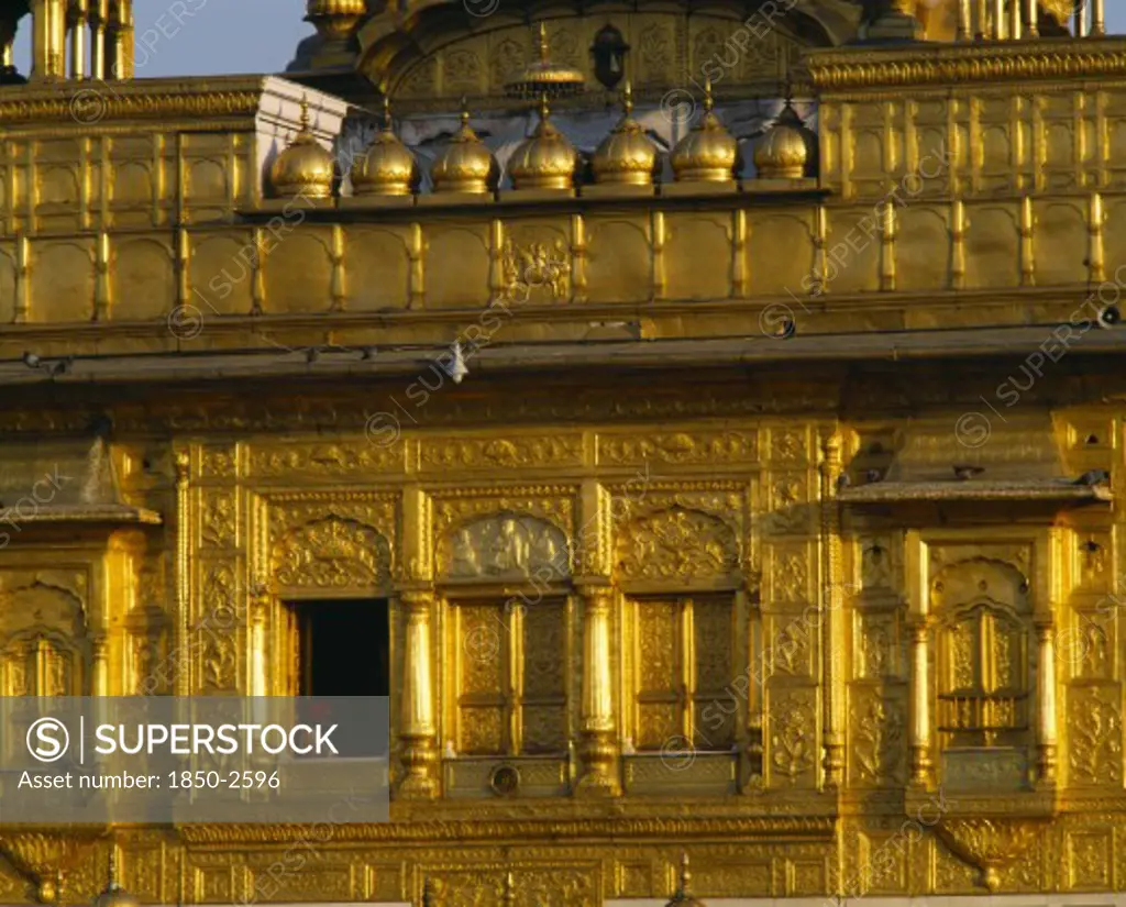 India, Punjab, Amritsar, The Golden Temple.  Detail Of Golden Exterior Wall With Man Framed In Window.