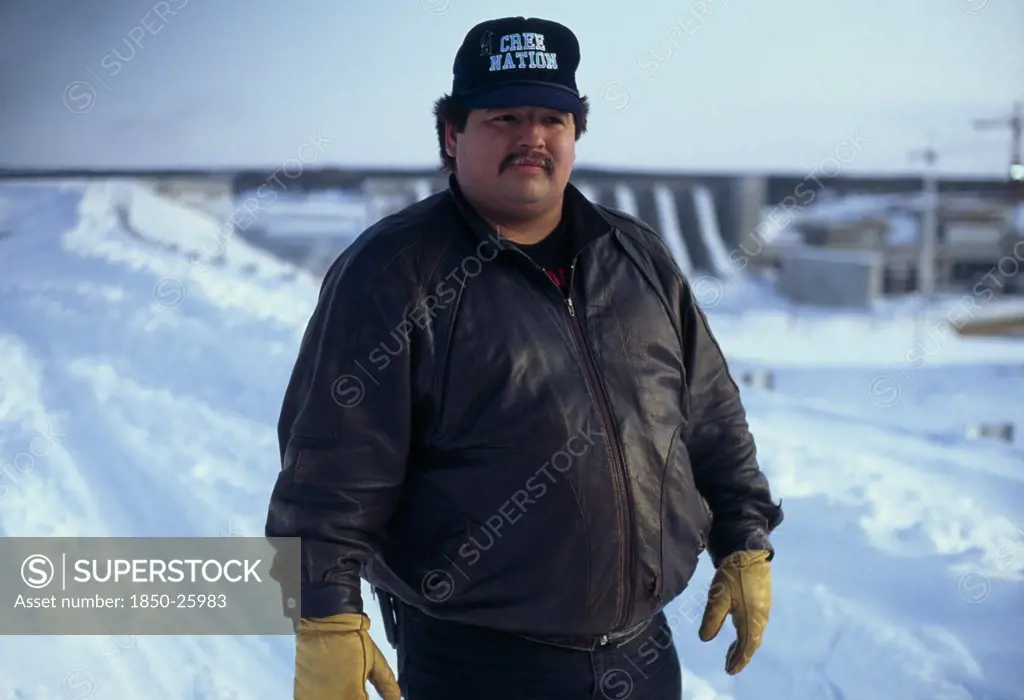 Canada, Quebec, James Bay, Man Named Larry Who Is A Cree Indigenous Activist Wearing A Cree Nation Baseball Cap Standing In The Snow In Front Of Hydro QuebecS Giant New Dam Project Which Has Ruined Cree Fishing Downstream Of The Dam