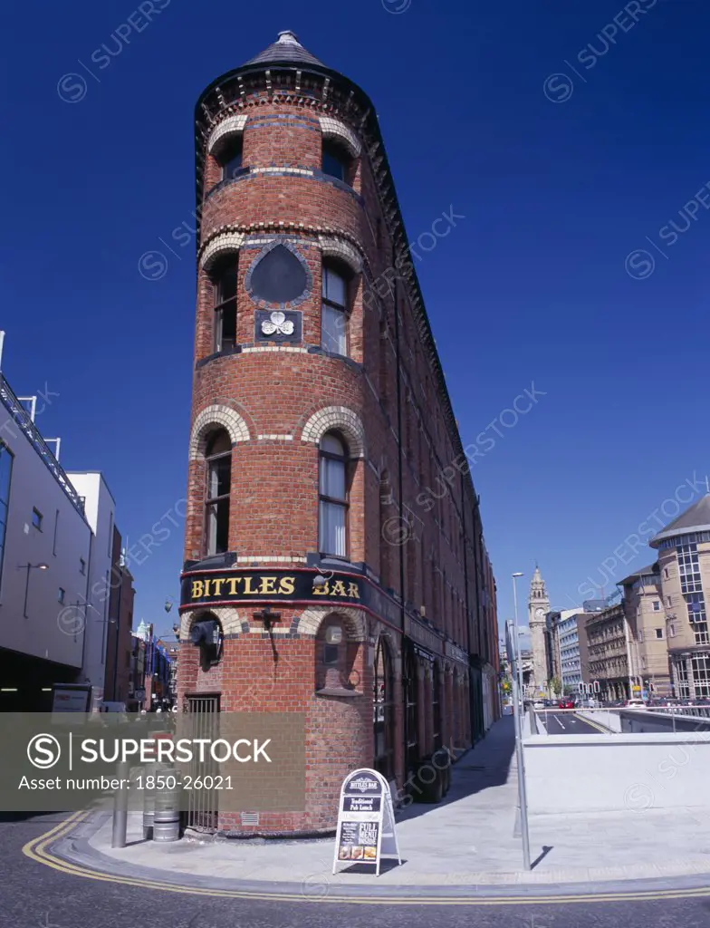 Ireland, North, Belfast, 'Bittles Bar, Brick Exterior Facade, A-Board Advertising Menu And Beer Barrels At Side With The Albert Memorial Clock Tower Seen Beyond.'