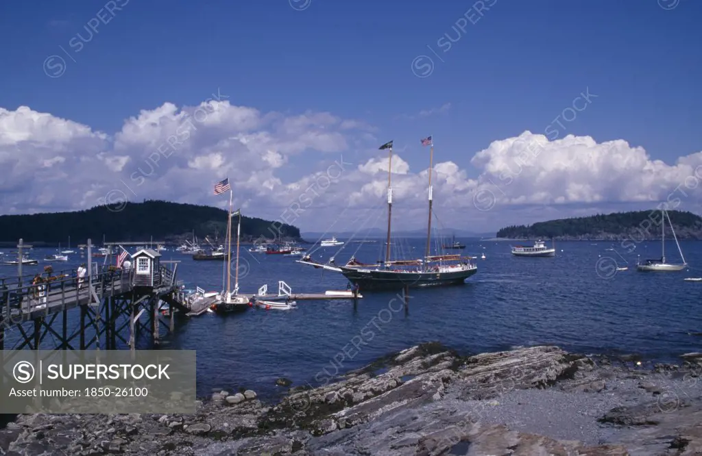 Usa, Maine, Bar Harbour, 'Wooden Jetty With Approaching Yacht, Various Boats On Water And Tree Covered Headland Beyond.'