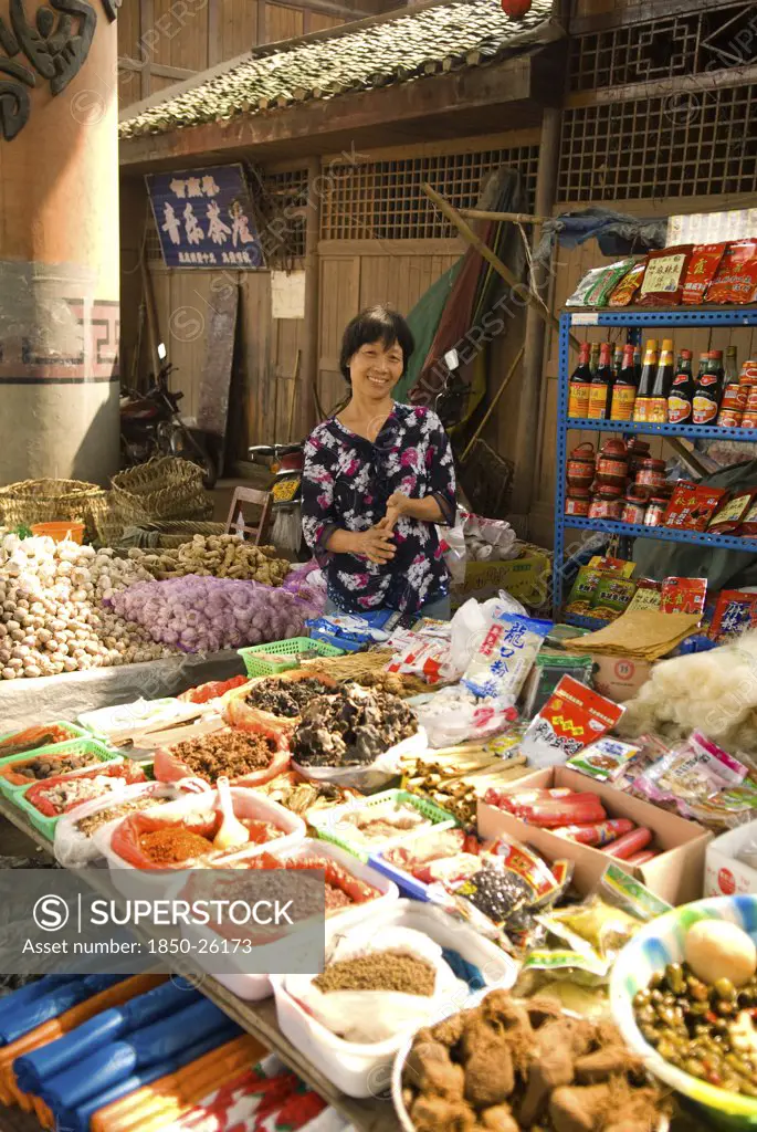 China, Sichuan Province, Chongqing, 'Street Market With A Smiling Woman Vendor Selling Spices, Garlic, Ginger And Other Foodstuffs Below Ciqiikou Ancient Town'