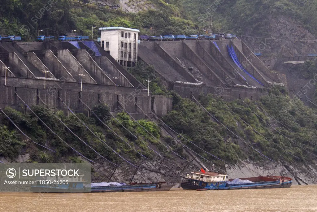 China, Hubei , Sandouping, Industrial Complex In The Wu Gorge. Line Of Trucks Bring Coal From The Mines And Dump Into Bunkers From Where It Flows Through Pipes To Coal Barges Waiting Below On The Yangtze River