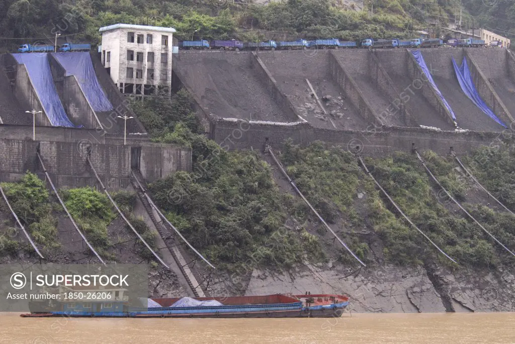 China, Hubei , Sandouping, Industrial Complex In The Wu Gorge. Line Of Trucks Bring Coal From The Mines And Dump Into Bunkers From Where It Flows Through Pipes To Coal Barges Waiting Below On The Yangtze River