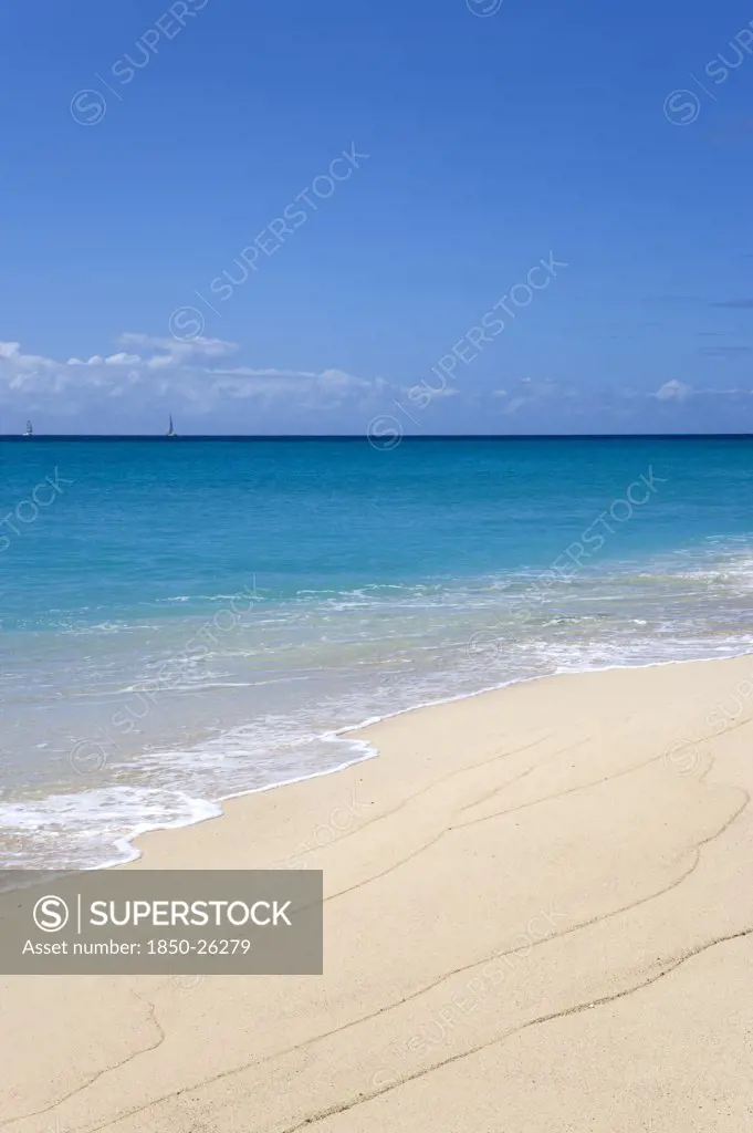 West Indies, St Vincent And The Grenadines, Canouan, South Glossy Beach In Glossy Bay With Waves Breaking On The Shoreline Of The Turqoise Sea And Yachts On The Horizon