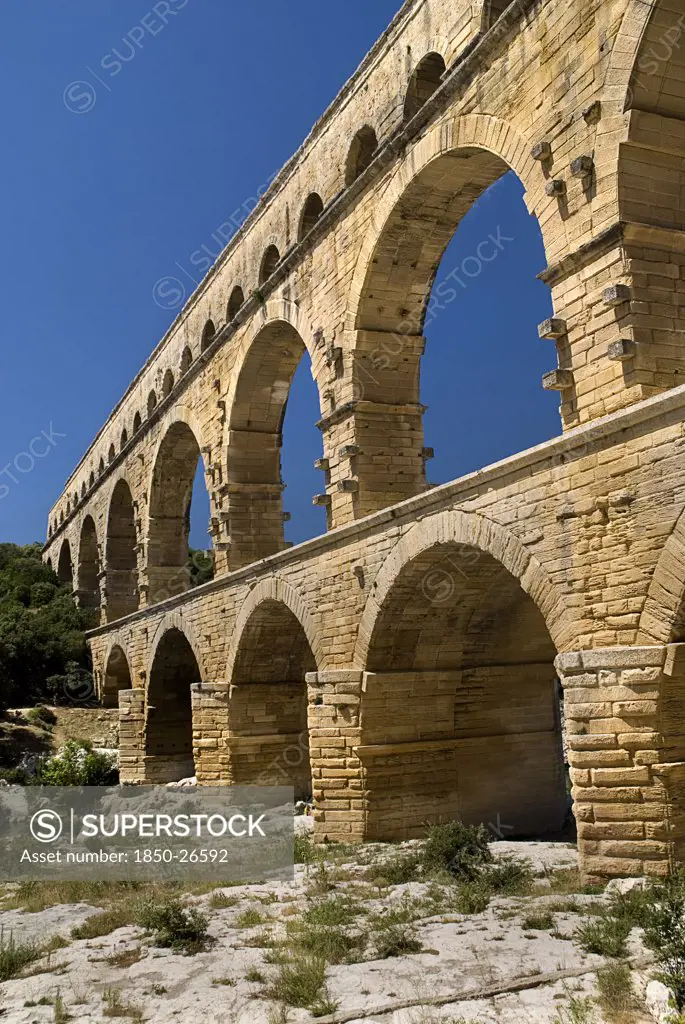 France, Provence Cote DAzur, Gard, Pont Du Gard.  Angled View Of Three Tiers Of Arches Of Roman Aqueduct From The West Side In Glowing Evening Light.