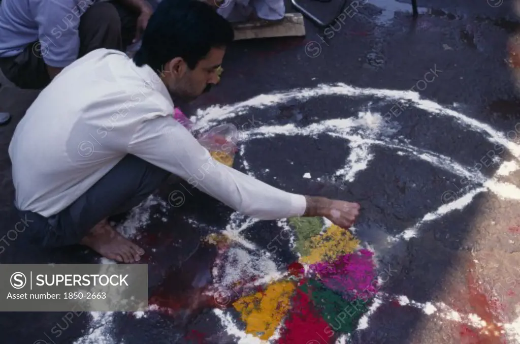 India, Delhi , Man Painting Wheel-Like Design On The Ground To Be Used As A Base For A Bonfire During The Holi Festival.