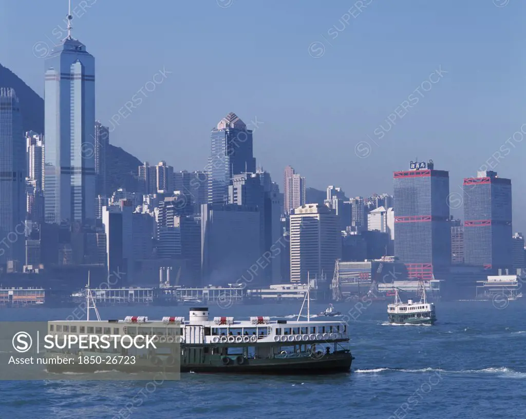 China, Hong Kong, Victoria Harbour, Star Ferries Crossing Victoria Harbour With High Rise Buildings On City Skyline Beyond.