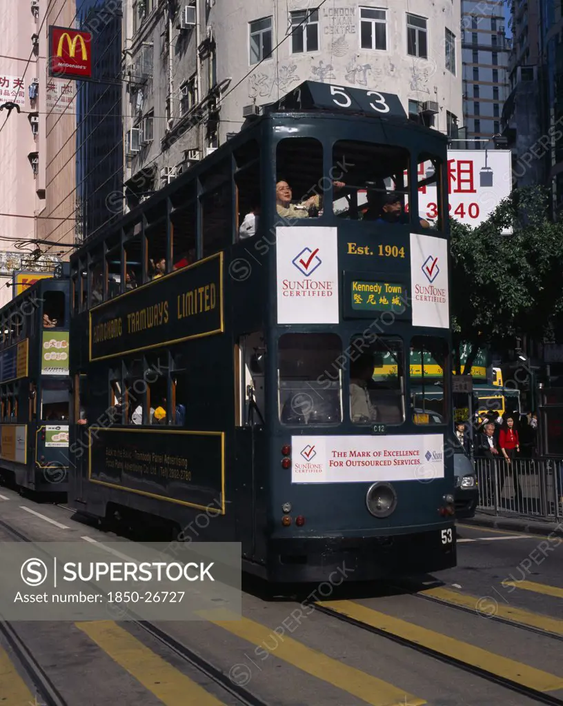 China, Hong Kong, Hong Kong Island Tram On City Street With High Rise Buildings And Advertising Hoardings.