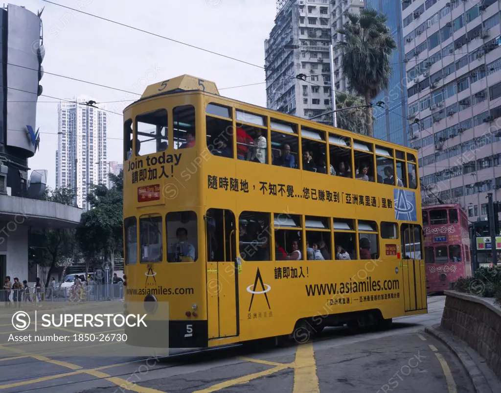 China, Hong Kong, 'Hong Kong Island Tram With Passengers On Top Deck Looking Out Of Windows, Advertising Printed Along The Side And High Rise Buildings Behind.  '