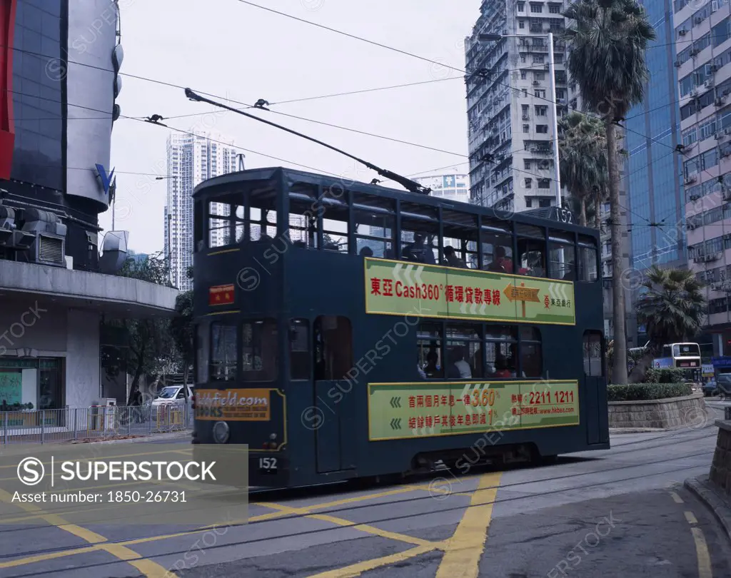 China, Hong Kong, Hong Kong Island Tram With Advertising Printed Along Side And High Rise Buildings Behind.