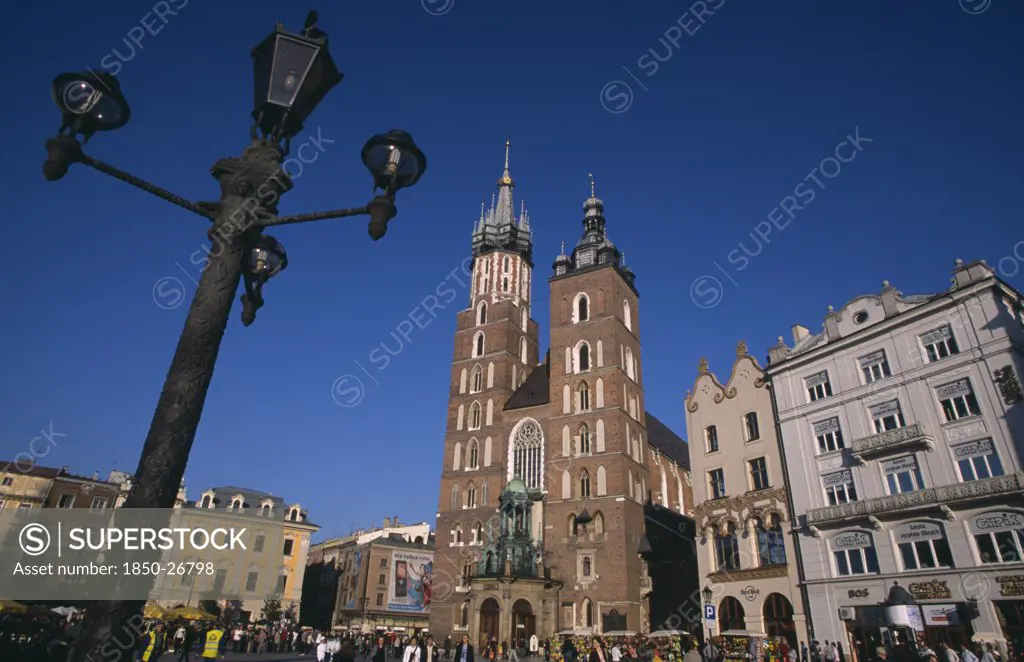 Poland, Krakow, Mariacki Basilica Or Church Of St Mary.  Gothic  Red Brick Exterior Built In The Fourteenth Century Overlooking The Main Market Square With Street Lamp In Foreground.