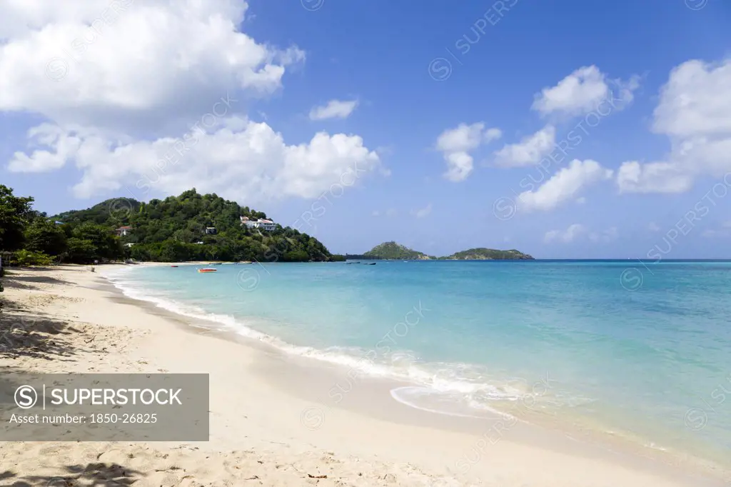 West Indies, Grenada, Carriacou, The Calm Clear Blue Water Breaking On Paradise Beach In L'Esterre Bay With Point Cistern And The Sister Rocks In The Distance