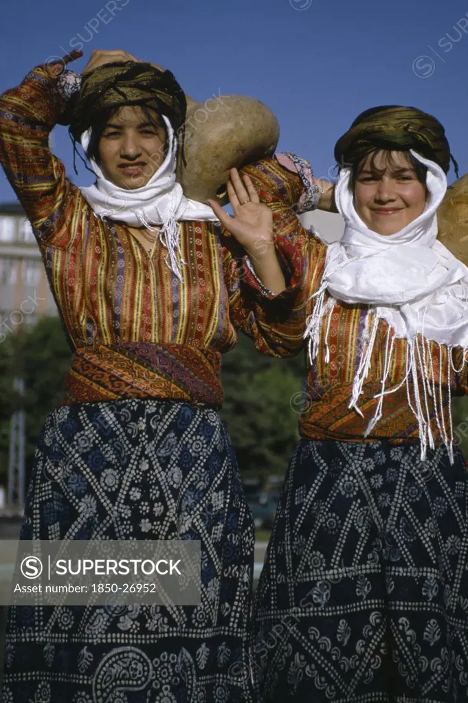 Turkey, East, People, Three Quarter Portrait Of Two Girls Carrying Gourd Vessels.