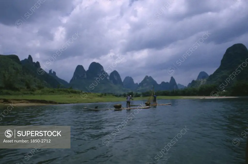 China, Guangxi, Guilin, Cormorant Fishermen On Rafts On The River Li With Limestone Karst Mountains In The Distance