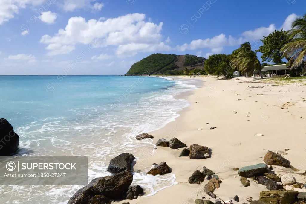 West Indies, St Vincent & The Grenadines, Canouan, South Glossy Beach In Glossy Bay With Footprints In The Sand And Waves From The Turqoise Sea Breaking On The Shore.
