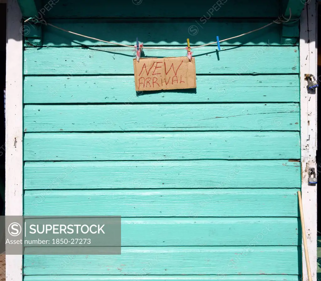 West Indies, Grenada, Carriacou, New Arrival Sign On The Padlocked Turqoise Shutter Of A Shop In Hillsborough.