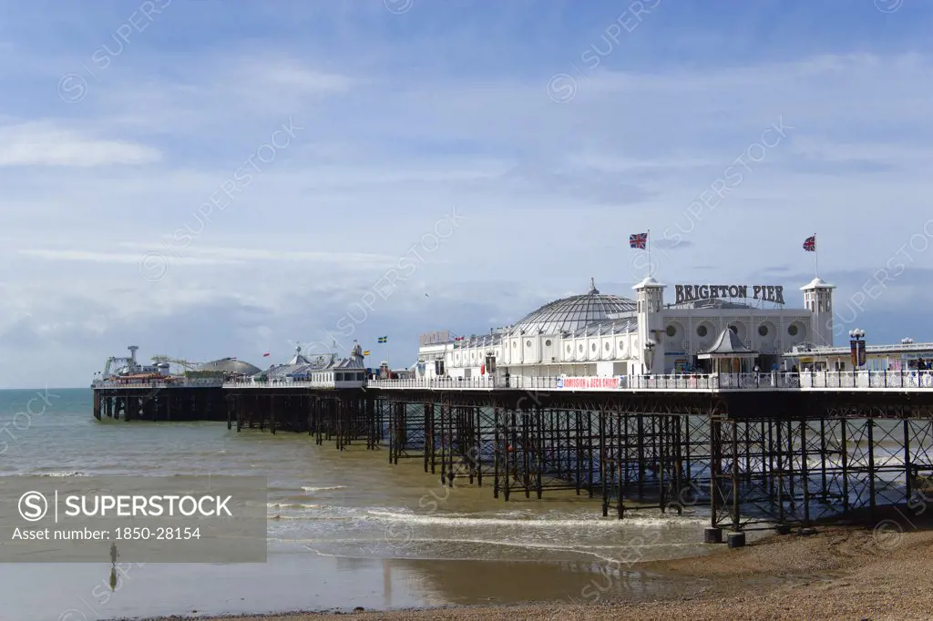 England, East Sussex, Brighton, The Pier At Low Tide With A Woman Walking Towards The Water.