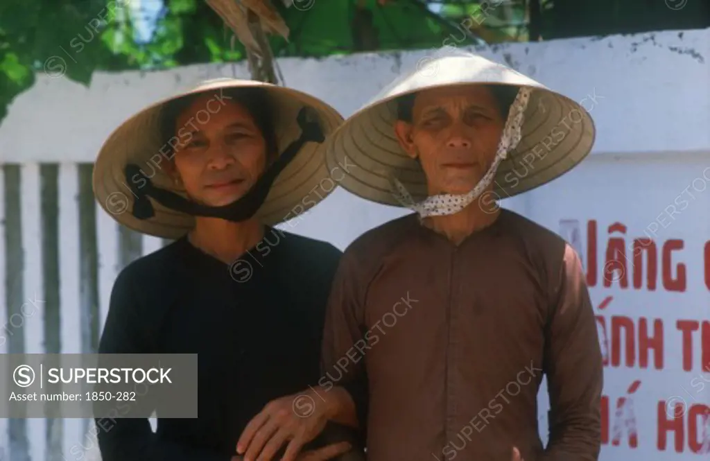 Vietnam, Danang, 'Mother And Daughter Standing With Linked Arms, Wearing Traditional Straw Hats.  '