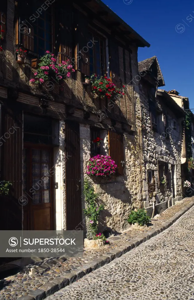 France, Aquitaine, Bergerac, Terrace Row Of Stone Houses With Wooden Shutters And Hanging Flower Baskets Outside.