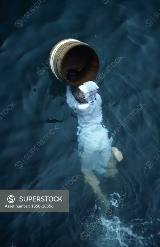 Japan, Honshu, Toba, Traditional Female Pearl Diver Swimming In The Water With Wooden Barrel For Collecting Oysters At The Mikimoto Pearl Farm In Mie Prefecture In Kansai Region.