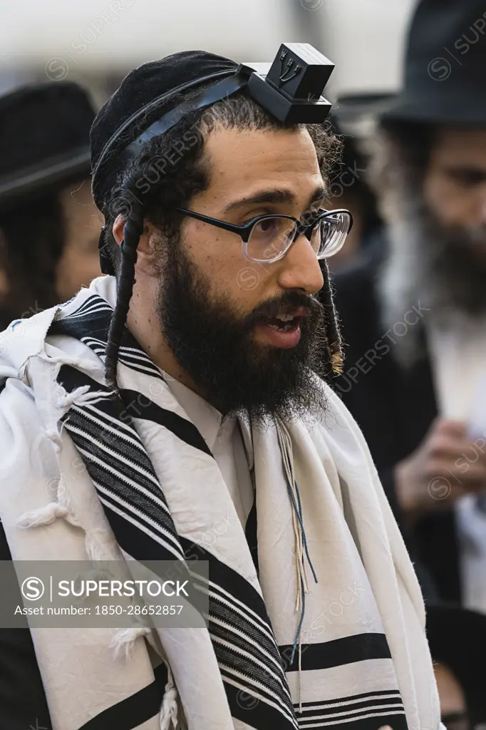 Israel, Jerusalem, Western Wall, An Haredic Jewish man in the traditional tallit - prayer shawl -and tellifin or phylactery chants in worship at the Western Wall of the Temple Mount in the Jewish Quarter of the Old City.