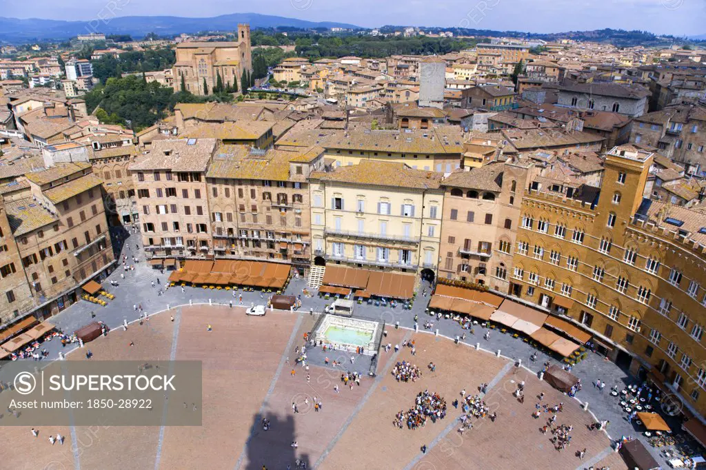 Italy, Tuscany, Siena, View Over The Piazza Del Campo And The North Of The City With People Walking In The Square Past The Palazzi And Restaurants That Border It.