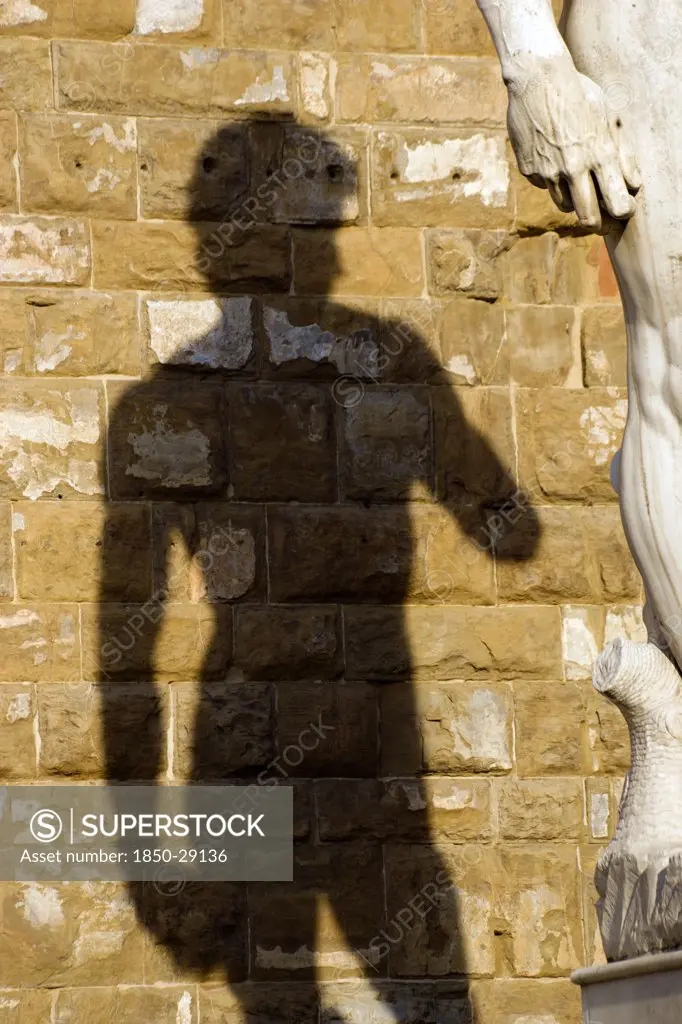 Italy, Tuscany, Florence, Shadow Of The Replica Renaissance Statue Of David By Michelangelo On The Wall Of The Palazzo Vecchio In The Piazza Della Signoria.