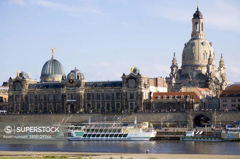 Germany, Saxony, Dresden, The City Skyline With Cruise Boats Moored On The River Elbe In Front Of The Embankment Buildings On The Bruhl Terrace Busy With Tourists Of The Art Academy And The Restored Baroque Frauenkirche Church Of Our Lady Dome.