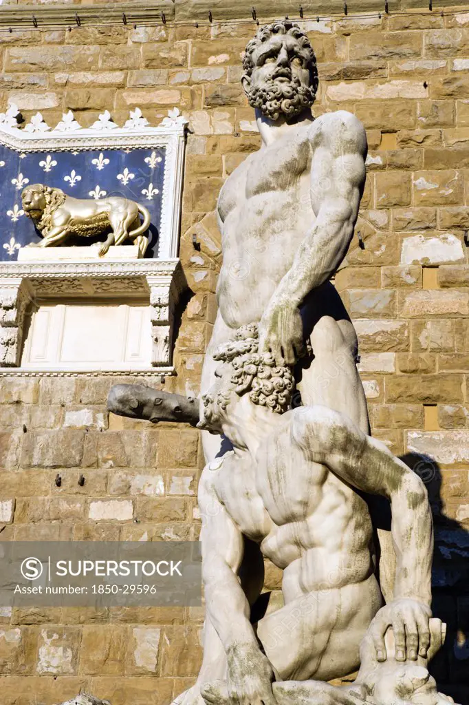 Italy, Tuscany, Florence, The 1533 Statue Of Hercules And Cacus By Bandinelli Seen Through The Legs Of A Stone Lion Outside The Palazzo Vecchio In The Piazza Della Signoria.