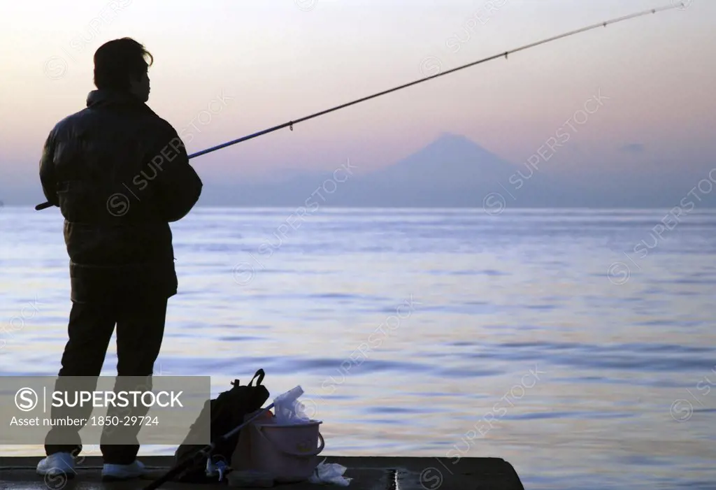 Japan, Honshu, Chiba, Tateyama  Man Fishing In Tokyo Bay  Mount Fuji Visible Across The Water.