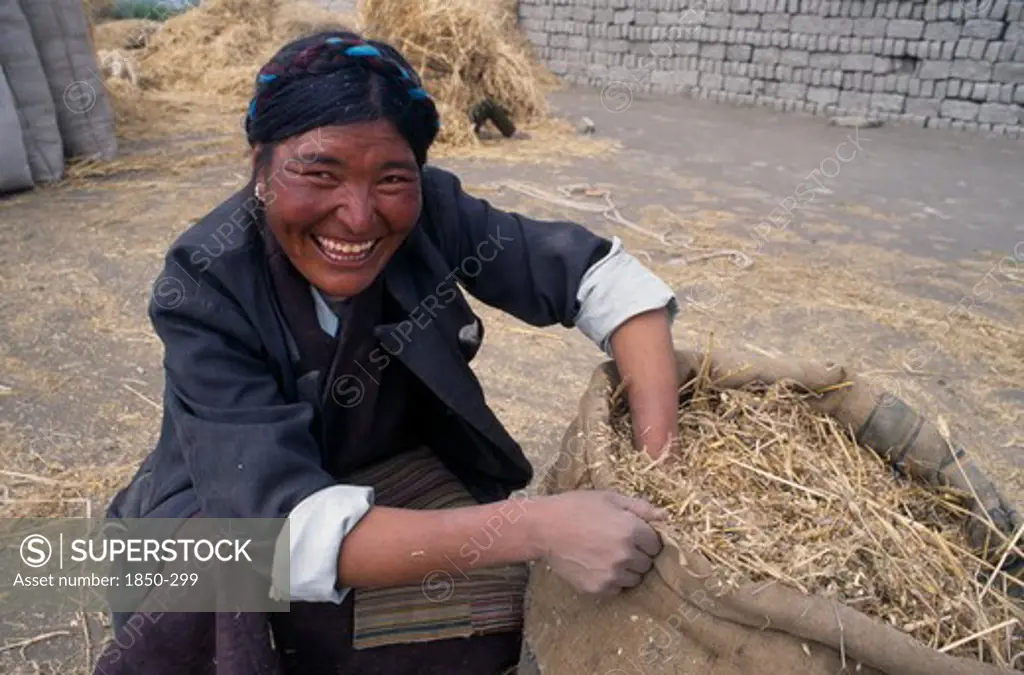 China, Tibet, Tandruk, Smiling Farm Worker With Bag Of Straw.