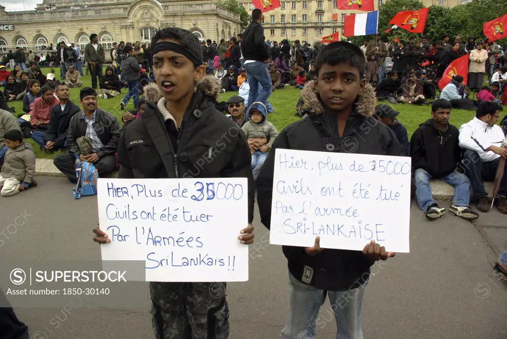 France, Ile De France, Paris, Esplanade Des Invalides Two Boys Stand In Front Of A Protest Of Tamil Tiger Supporters  Holding Signs Reading  Yesterday  More Than 35000 Civilians Were Killed By The Sri Lankan Army  In Protest To The War In Northern Sri Lanka.