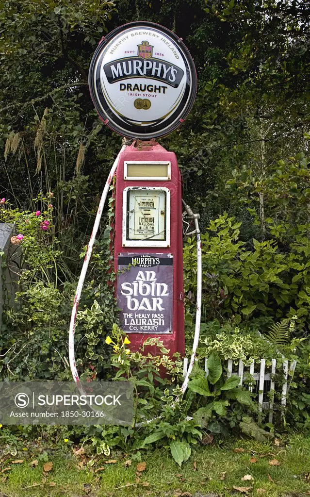 Ireland, County Kerry, Lauragh Village, Murphys Stout Sign Affixed To Old Petrol Pump With Advert For Bar