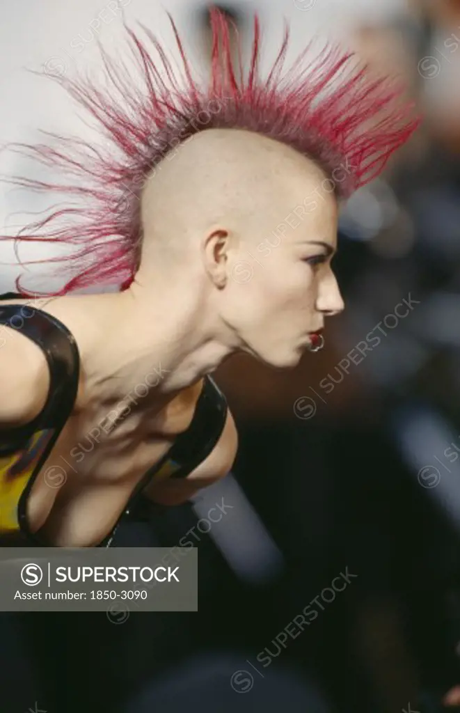 Fashion, Punk , Hairstyle / Piercing, Woman With Pink Spiked Hair Running In Narrow Strip Down Her Head And A Ring Through Her Bottom Lip At Alternative Fashion Show.