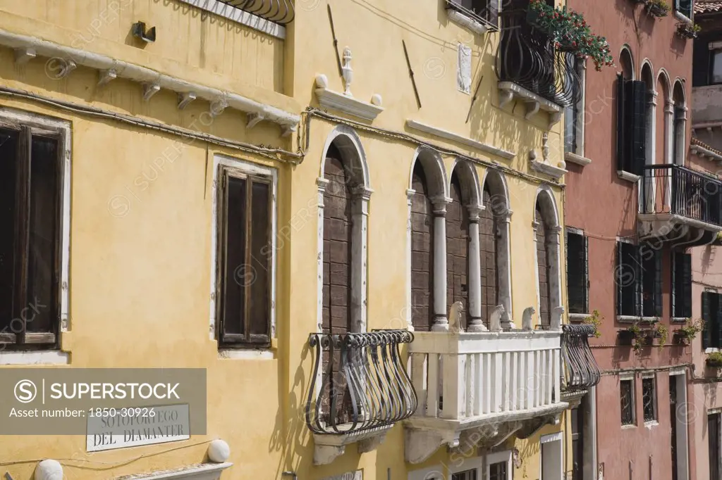 Italy Veneto Venice, Restored facades of canalside buildings painted pastel pink  terracotta and yellow with window balconies and shutters