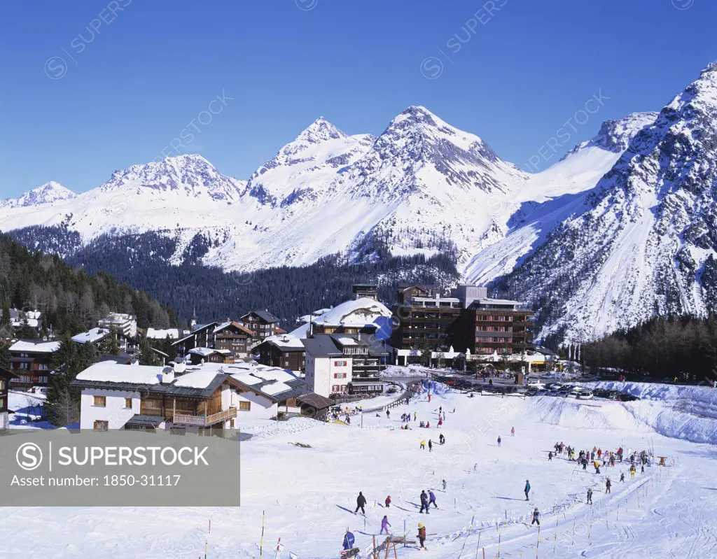 Switzerland Plessur Arosa, Ski resort with people skiing in the foreground and the Alps behind