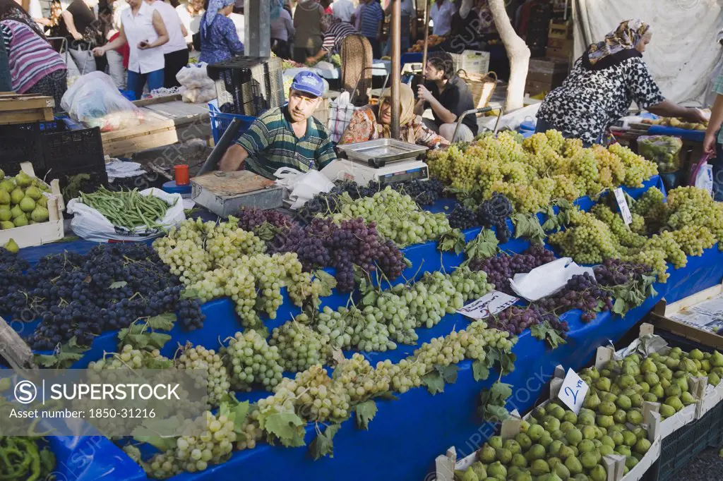 Turkey Aydin Province KUSAdasi, Stall with display of grapes  figs  beans and chilies for sale in busy market