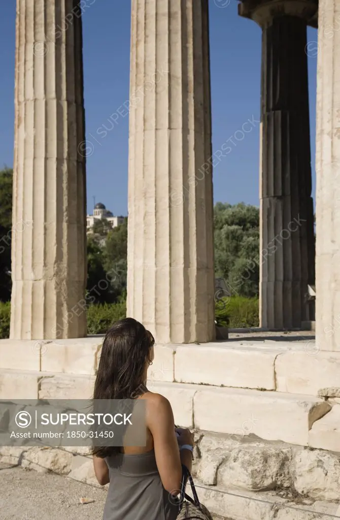 Greece Attica Athens, Young female tourist looking up at the Temple of Hephaestus  eastern face