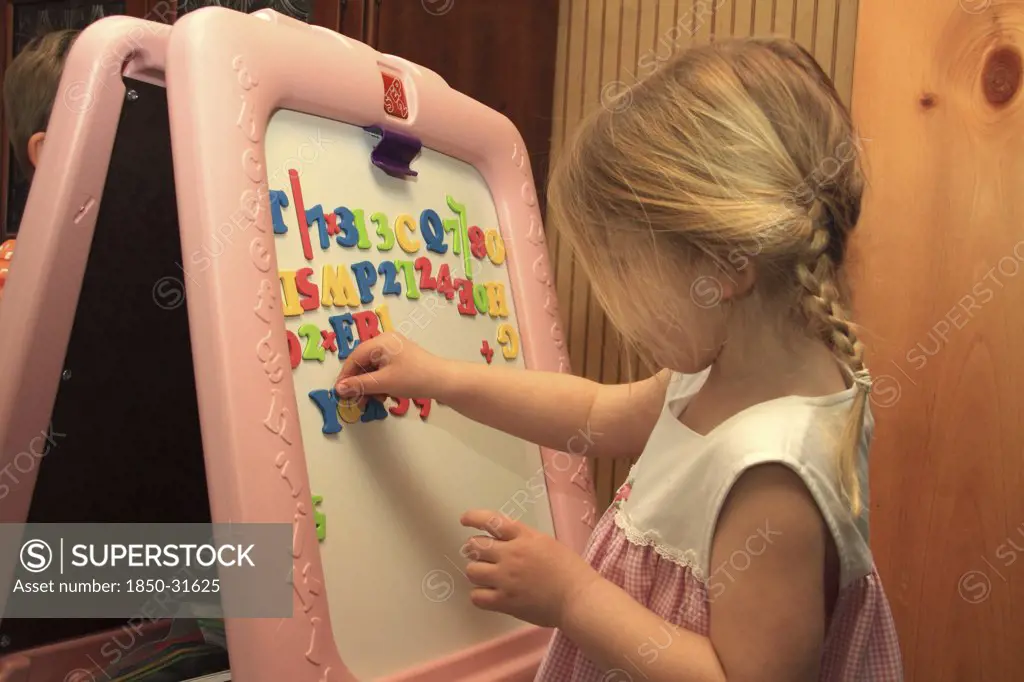 USA Children Education, Young girl  using magnetic letters on dry erase board in Keene  New Hampshire