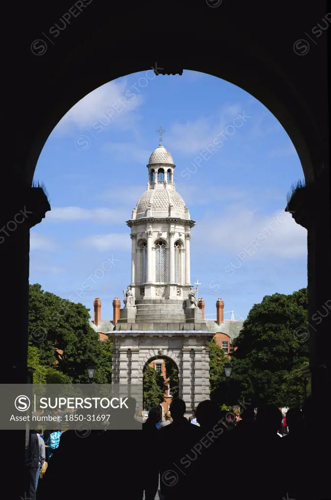 Ireland, County Dublin, Dublin City, Trinity College university with people walking through an arch at the entrance to Parliament Square leading towards the Campanile.