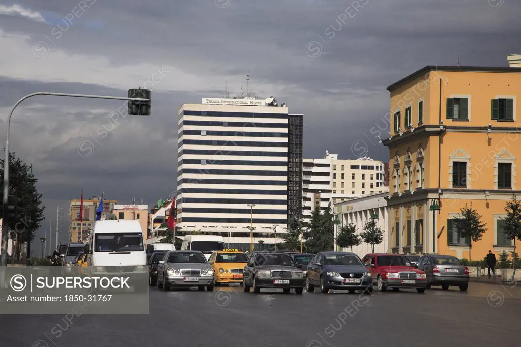 Albania, Tirane, Tirana, Traffic waiting at lights in Skanderbeg Square in front of the Tirana International Hotel.