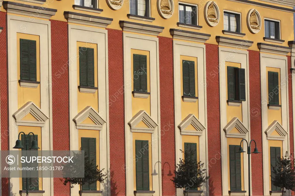 Albania, Tirane, Tirana, Detail of red and yellow exterior facade of government buildings on Skanderbeg Square.