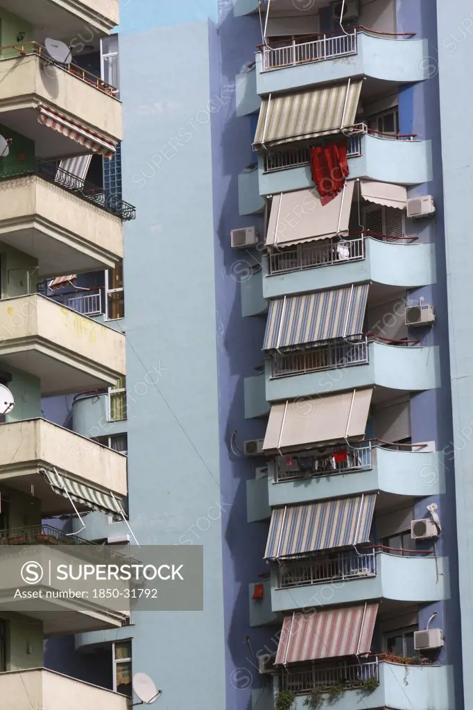 Albania, Tirane, Tirana, Detail of balconies and striped awnings on exterior facade of blue painted apartment block.