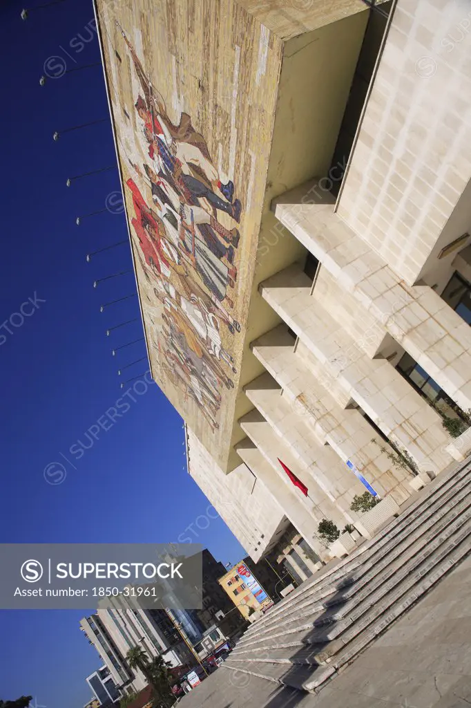 Albania, Tirane, Tirana, National History Museum. Angled view of exterior facade and entrance to the National History Museum in Skanderbeg Square with mosaic representing the development of Albanias history. City buildings beyond.