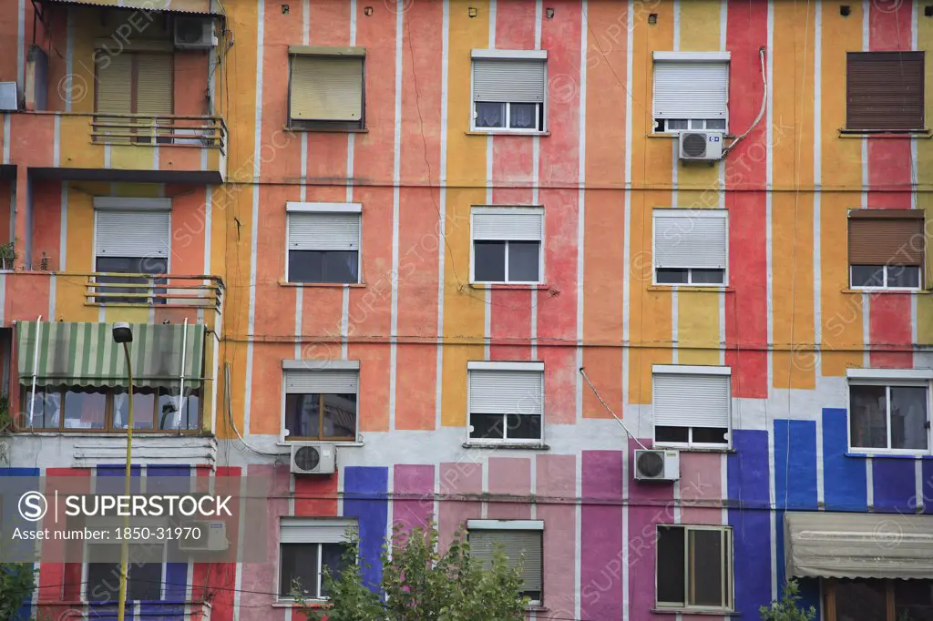 Albania, Tirane, Tirana, Detail of exterior facade of apartment block painted in stripes of different colours with multiple windows and balconies.