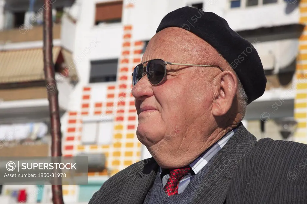 Albania, Tirane, Tirana, Head and shoulders portrait of an elderly man wearing sunglasses and a beret. Profile left.