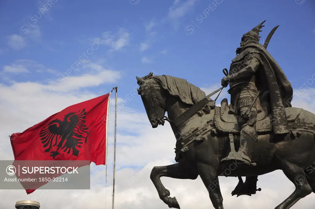 Albania, Tirane, Tirana, Equestrian statue of the national hero George Castriot Skanderbeg with national flag depicting double headed eagle against red background flying at side.