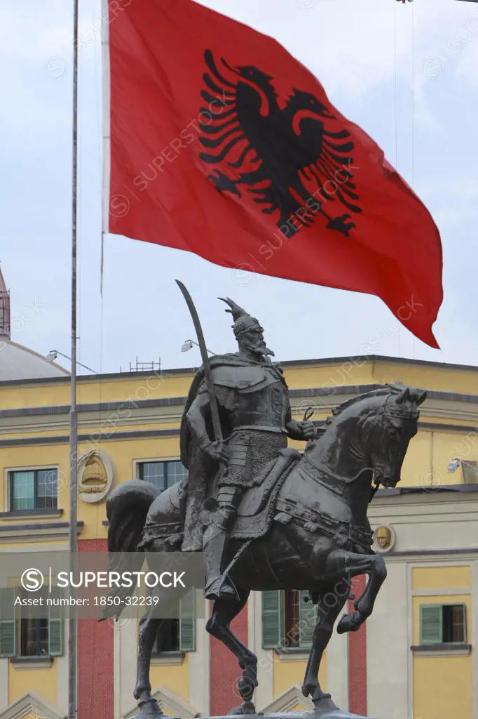 Albania, Tirane, Tirana, National flag depicting two headed eagle flying above equestrian statue of George Castriot Skanderbeg  the national hero of Albania.